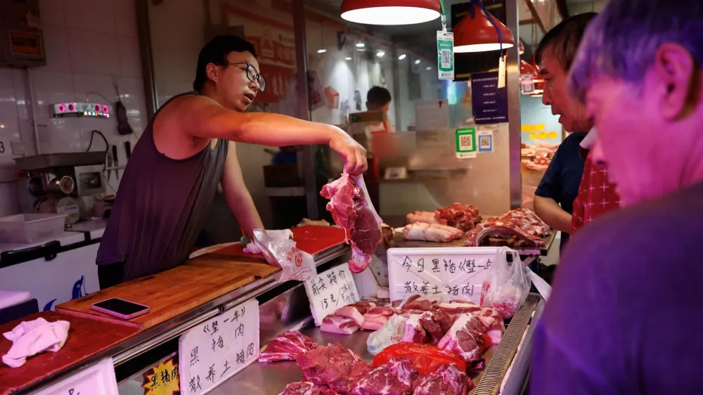 A pork vendor attends to a customer at a morning market in Beijing, China August 9, 2023. REUTERS/Tingshu Wang