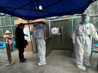 A medical worker in a protective suit checks a thermometer for a patient at the entrance to the fever clinic of the Central Hospital of Wuhan, amid of the coronavirus disease (COVID-19) outbreak, in Wuhan, Hubei province, China December 31, 2022. REUTERS/Tingshu Wang
