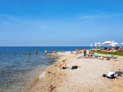 Izo, Slovenia &ndash; February 04, 2021: People on beach in Izola, Slovenia. Sunny summer day, palm trees, city, town, horizon, sea, vacation, travel.