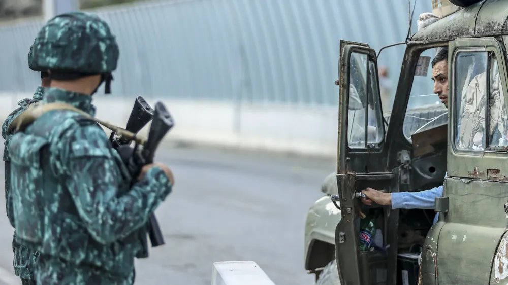 Sergey Astsetryan, an ethnic Armenian resident of Nagorno-Karabakh, right, says goodbye to Azerbaijani border guard servicemen after they checked his Soviet-made vehicle at the Lachin checkpoint on the way from Nagorno-Karabakh to Armenia, in Azerbaijan, Sunday, Oct. 1, 2023. Astsetrayn was one of the last residents of Nagorno-Karabakh to drive out of the region in his own vehicle as part of a grueling weeklong exodus of over 100,000 people &mdash; more than 80% of the residents &mdash; after Azerbaijan reclaimed the area in a lightning military operation. (AP Photo/Aziz Karimov)