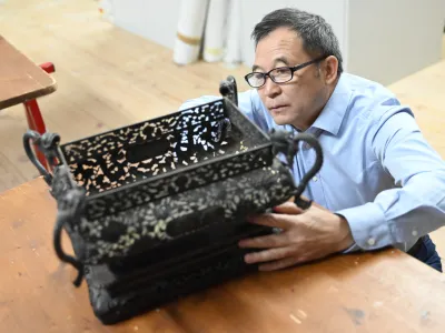 Kustos Guo Fuxiang si ogleduje enega od predmetov, ki jih je Sku&scaron;ek pred sto leti v Slovenijo pripeljal iz Kitajske.