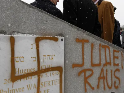 France's Interior Minister Brice Hortefeux (R) walks next to a tombstone desecrated by vandals with a Nazi swastika and the slogan "Jews out" in the Jewish Cemetery of Cronenbourg near Strasbourg January 28, 2010. Thirty-one tombs were found desecrated on Wednesday in the Jewish cemetery of Cronenbourg, the biggest Jewish cemetery of Strasbourg. REUTERS/Vincent Kessler (CRIME LAW RELIGION POLITICS)