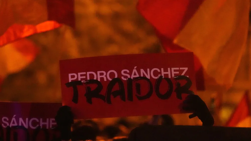 A sign reading 'Pedro Sanchez, Traitor' is held up during a protest by right wing demonstrators near the national headquarters of Spain's Socialist Party in Madrid, Spain, Tuesday, Nov. 7, 2023. The Spanish capital saw its second night in a row of clashes between police and protesters who oppose negotiations between Spain's acting government and Catalan separatist parties over a&nbsp;possible amnesty&nbsp;for thousands involved in Catalonia's independence movement. (AP Photo/Paul White)