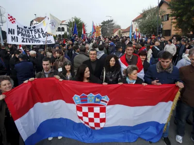 People carry a Croatian national flag during a ceremony to mark the 22th anniversary of Vukovar's fall, in downtown Vukovar November 18, 2013. The Danube town of Vukovar was entirely destroyed 22 years ago by Serb paramilitary forces backed by units of the former Yugoslav army at the beginning of Croatia's 1991-95 independence war. REUTERS/Antonio Bronic (CROATIA - Tags: CONFLICT ANNIVERSARY SOCIETY)