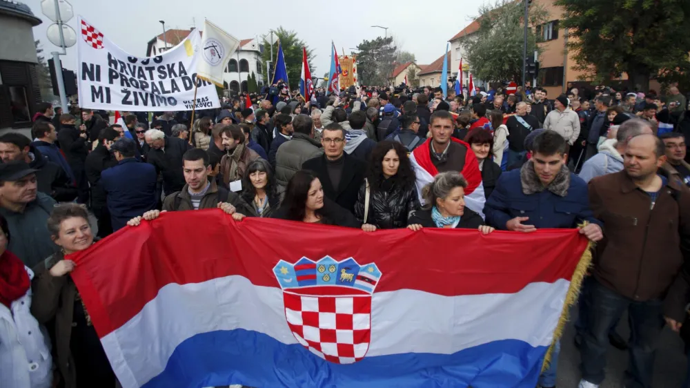 People carry a Croatian national flag during a ceremony to mark the 22th anniversary of Vukovar's fall, in downtown Vukovar November 18, 2013. The Danube town of Vukovar was entirely destroyed 22 years ago by Serb paramilitary forces backed by units of the former Yugoslav army at the beginning of Croatia's 1991-95 independence war. REUTERS/Antonio Bronic (CROATIA - Tags: CONFLICT ANNIVERSARY SOCIETY)
