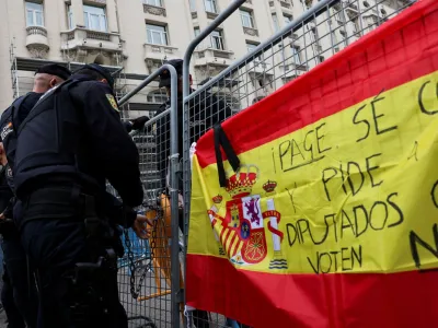 Police members work next to a Spanish flag hanged on fencing during a protest outside the Spanish parliament, as the investiture debate kicks off after Spain's socialists reached a deal with the Catalan separatist Junts party for government support, a pact which involves amnesties for people involved with Catalonia's failed 2017 independence bid, in Madrid, Spain November 15, 2023. REUTERS/Violeta Santos Moura