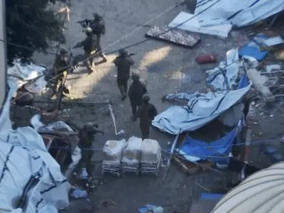 In this image taken from a video released by the Israeli Defense Forces on Tuesday, Nov. 15, 2023, Israeli soldiers walk in the area of Al-Shifa hospital in Gaza City. The Israeli military released footage on Tuesday that it said shows joint operational activity of two army brigades in its advancement on the ground in Gaza Strip. (Israel Defense Forces via AP)