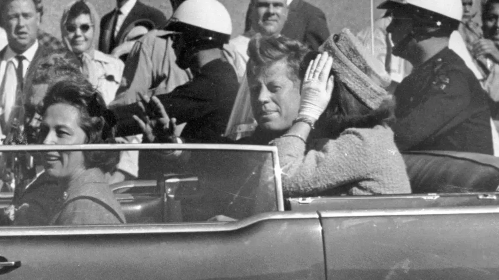 FILE - President John F. Kennedy waves from his car in a motorcade approximately one minute before he was shot, Nov. 22, 1963, in Dallas. Riding with President Kennedy are first lady Jacqueline Kennedy, right, Nellie Connally, second from left, and her husband, Texas Gov. John Connally, far left. The 60th anniversary of President Kennedy's assassination, marked on Wednesday, Nov. 22, 2023, finds his family, and the country, at a moment many would not have imagined in JFK's lifetime. (AP Photo/Jim Altgens, File)