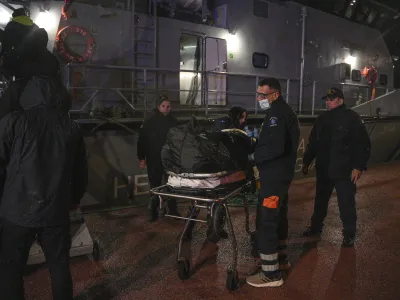 Paramedics carry the body of a crew member of a ship, on the northeastern Aegean Sea island of Lesbos, Greece, Sunday, Nov. 26, 2023. A cargo ship sank off the Greek island of Lesbos early Sunday, leaving 13 crew members missing and one rescued, authorities said. The Raptor, registered in the Comoros, was on its way to Istanbul from Alexandria, Egypt, carrying 6,000 tons of salt, the coast guard said. It had a crew of 14, including eight Egyptians, four Indians and two Syrians, the coast guard said.(AP Photo/Panagiotis Balaskas)