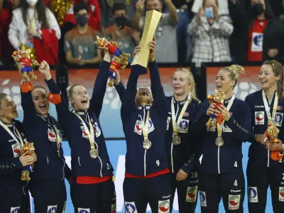 Norway's Mora Mork lifts the trophy as team players celebrate after beating France during the final of the Women's Handball World Championship in Granollers, Spain, Sunday, Dec. 19, 2021. (AP Photo/Joan Monfort)