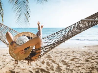 Summer travel vacation concept, Happy traveler asian woman with white bikini relax in hammock on beach in Koh mak, Thailand