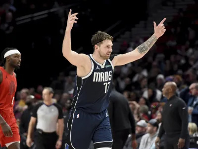 Dallas Mavericks guard Luka Doncic (77) reacts after a teammate hits a shot late in the game as Portland Trail Blazers forward Jerami Grant, left, looks on during the second half of an NBA basketball game in Portland, Ore., Saturday, Dec. 16, 2023. (AP Photo/Steve Dykes)