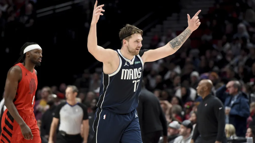 Dallas Mavericks guard Luka Doncic (77) reacts after a teammate hits a shot late in the game as Portland Trail Blazers forward Jerami Grant, left, looks on during the second half of an NBA basketball game in Portland, Ore., Saturday, Dec. 16, 2023. (AP Photo/Steve Dykes)