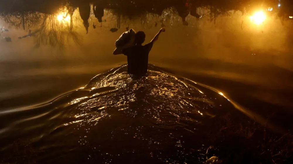 A Venezuelan migrant crosses the Rio Bravo river, the border between the United States and Mexico, with the intention of turning themselves in to the U.S. Border Patrol agents to request asylum, during a day of low temperatures, as seen from Ciudad Juarez, Mexico December 28, 2023. REUTERS/Jose Luis Gonzalez   TPX IMAGES OF THE DAY