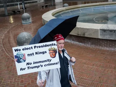 A person holds a placard, on the day of a hearing on former U.S. President Donald Trump's claim of immunity in the federal case accusing him of illegally attempting to overturn his 2020 election defeat, at U.S. District Court in Washington, U.S., January 9, 2024. REUTERS/Nathan Howard