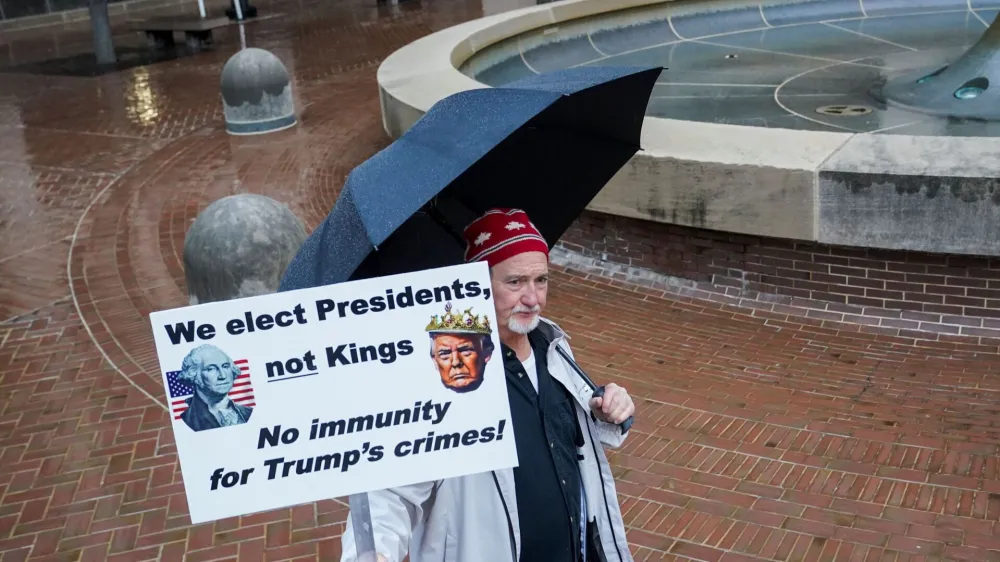 A person holds a placard, on the day of a hearing on former U.S. President Donald Trump's claim of immunity in the federal case accusing him of illegally attempting to overturn his 2020 election defeat, at U.S. District Court in Washington, U.S., January 9, 2024. REUTERS/Nathan Howard