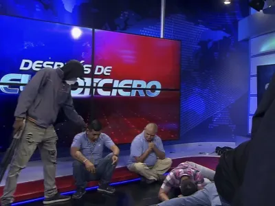 Oboroženi in zamaskirani mo&scaron;ki v studiu telvizije TC ob novinarjih. Končalo se je brez strelov.