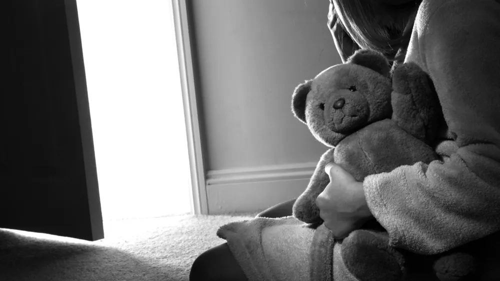 BTA0N2 Young girl sitting holding a teddy bear, back view.<br>spolna zloraba otroci otrok