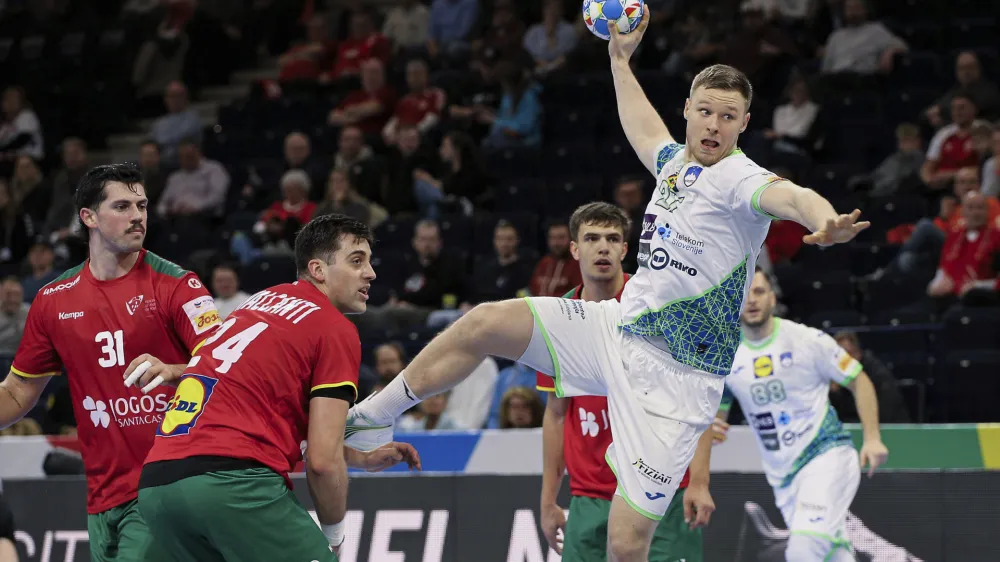 Slovenia's Kristjan Horzen, right, takes a shot during the European Handball Championship main round, Group 2 between Slovenia and Portugal at the Barclaycard Arena, in Hamburg, Germany, Friday Jan. 19, 2024. (Claus Bergmann/dpa via AP)