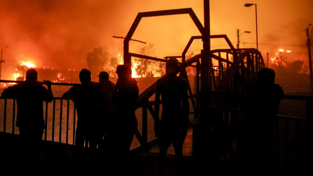 Neighbors watch as a forest fire engulfs buildings in Vina del Mar, Chile, Friday, Feb. 2, 2024. (AP Photo/Cristobal Basaure)