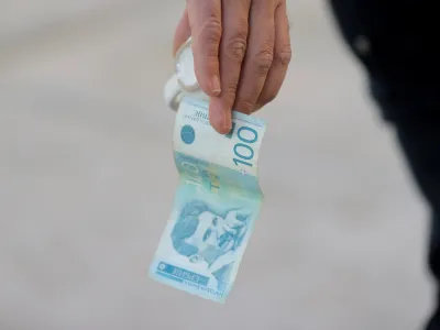 A man holds a dinar currency and a coffee cup in Mitrovica, Kosovo, February 1, 2024. The Kosovo government will ban the Serbian dinar in minority regions despite warnings from the EU and the U.S. that such could fuel ethnic tensions in the volatile north. REUTERS/Valdrin Xhemajj