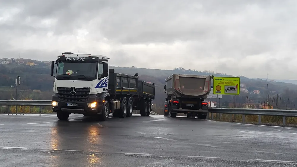 Tovornjaki nenehno odvažajo izkopani material z gradbi&scaron;č (na fotografiji Dekani).