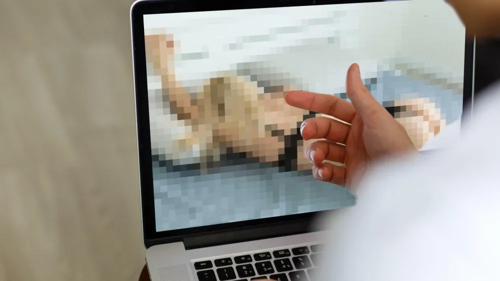 2J8518C closeup of a young caucasian man watching a nude woman in his computer