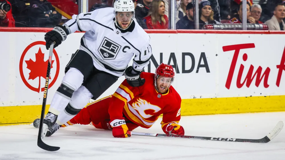 Feb 27, 2024; Calgary, Alberta, CAN; Los Angeles Kings center Anze Kopitar (11) and Calgary Flames center Kevin Rooney (21) battles for the puck during the second period at Scotiabank Saddledome. Mandatory Credit: Sergei Belski-USA TODAY Sports