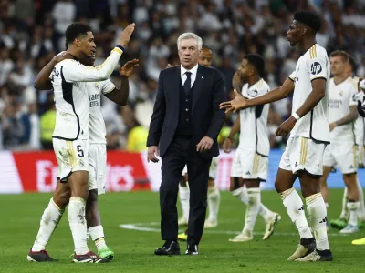 Soccer Football - LaLiga - Real Madrid v FC Barcelona - Santiago Bernabeu, Madrid, Spain - April 21, 2024 Real Madrid's Jude Bellingham, Vinicius Junior and Aurelien Tchouameni celebrate after the match as coach Carlo Ancelotti looks on REUTERS/Susana Vera
