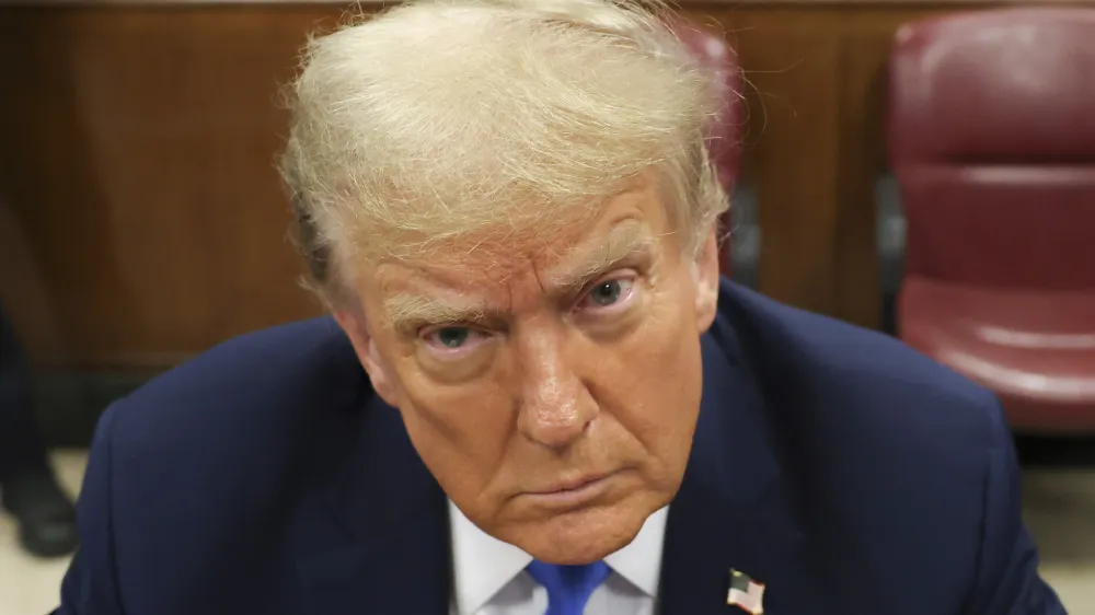Former president Donald Trump, center, awaits the start of proceedings at Manhattan criminal court, Monday, April 22, 2024, in New York. Opening statements in Donald Trump's historic hush money trial are set to begin. Trump is accused of falsifying internal business records as part of an alleged scheme to bury stories he thought might hurt his presidential campaign in 2016. (AP Photo/Yuki Iwamura, Pool)