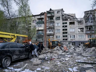 14 April 2023, Ukraine, Sloviansk: Residents push a damaged car in front of a damaged building in Sloviansk. Russian troops attacked eastern Ukrainian city Sloviansk on eastern Orthodox great Friday, causing at least 8 dead and 21 injured, including children and many buildings destroyed. Photo: Ashley Chan/SOPA Images via ZUMA Press Wire/dpa