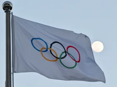 FILED - 14 February 2022, China, Beijing: The moon can be seen behind the flag with the Olympic rings. Photo: Peter Kneffel/dpa