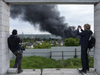 Foreign journalists report from an observation point while smoke rises after a Russian attack in Kharkiv, Ukraine, Friday, May 17, 2024. (AP Photo/Evgeniy Maloletka)