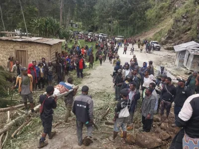 In this photo provided by the International Organization for Migration, an injured person is carried on a stretcher to seek medical assistance after a landslide in Yambali village, Papua New Guinea, Friday, May 24, 2024. More than 100 people are believed to have been killed in the landslide that buried a village and an emergency response is underway, officials in the South Pacific island nation said. The landslide struck Enga province, about 600 kilometers (370 miles) northwest of the capital, Port Moresby, at roughly 3 a.m., Australian Broadcasting Corp. reported. (Benjamin Sipa/International Organization for Migration via AP)