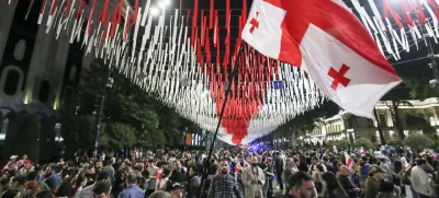 Demonstrators with a Georgian national flag gather at the Parliamentary building during an opposition protest against the foreign influence bill in Tbilisi, Georgia, Tuesday, May 28, 2024. The Georgian parliament has overridden a presidential veto of the "foreign agents" legislation that has fueled Western concerns and sparked massive protests for weeks. (AP Photo/Zurab Tsertsvadze)