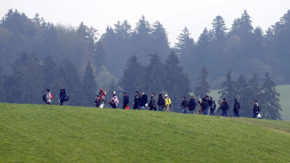 File photo of migrants crossing a field as they walk from the Austrian village of Kollerschlag towards the Austrian-German border in Wegscheid near Passau, Austria, October 20, 2015. In September, the leaders of Austria and Germany took one of the most pivotal decisions of Europe's refugee crisis, throwing open their borders to tens of thousands of migrants piling up in Hungary. Nearly half a year on, however, the display of unity over the Sept. 5-6 weekend is a distant memory. In a sign of how deep Europe's divisions over refugees have become, Berlin and Vienna snipe at each other almost daily. REUTERS/Michael Dalder/Files