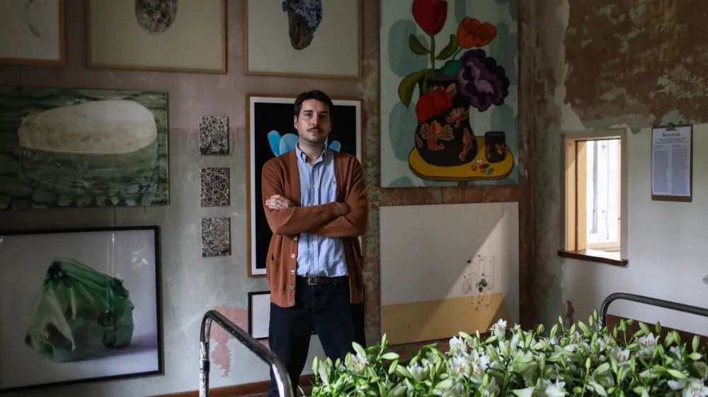 Postelja z belimi lilijami, simbolom žalovanja? Avtor Boris Beja jo je poimenoval Sanje na prehodu. Kustos Jure Kirbi&scaron; (na fotografiji) jo je uvrstil med tihožitja.&nbsp;