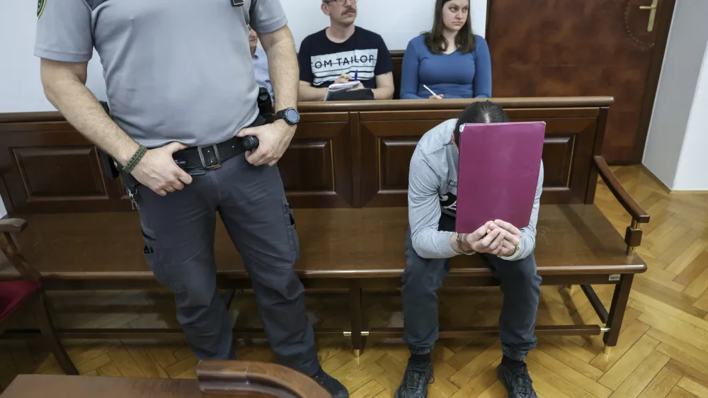 Luka Bohnec, ki se na fotografiji skriva za mapo, ne priznava krivde za poskus uboja oktobra lani. Se je pa za svoje dejanje opravičil in poudaril, da nikomur ni želel storiti nič žalega.&nbsp;