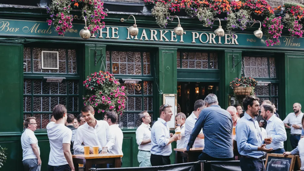 London, UK - July 23, 2019: People standing and drinking outside The Market Porter English pub in Borough Market, one of the largest and oldest food markets in London. Selective focus.