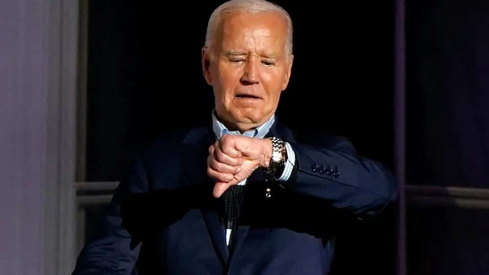 U.S. President Joe Biden looks at his watch as he stands on the balcony during an Independence Day celebration on the South Lawn of the White House in Washington, U.S., July 4, 2024. REUTERS/Elizabeth Frantz