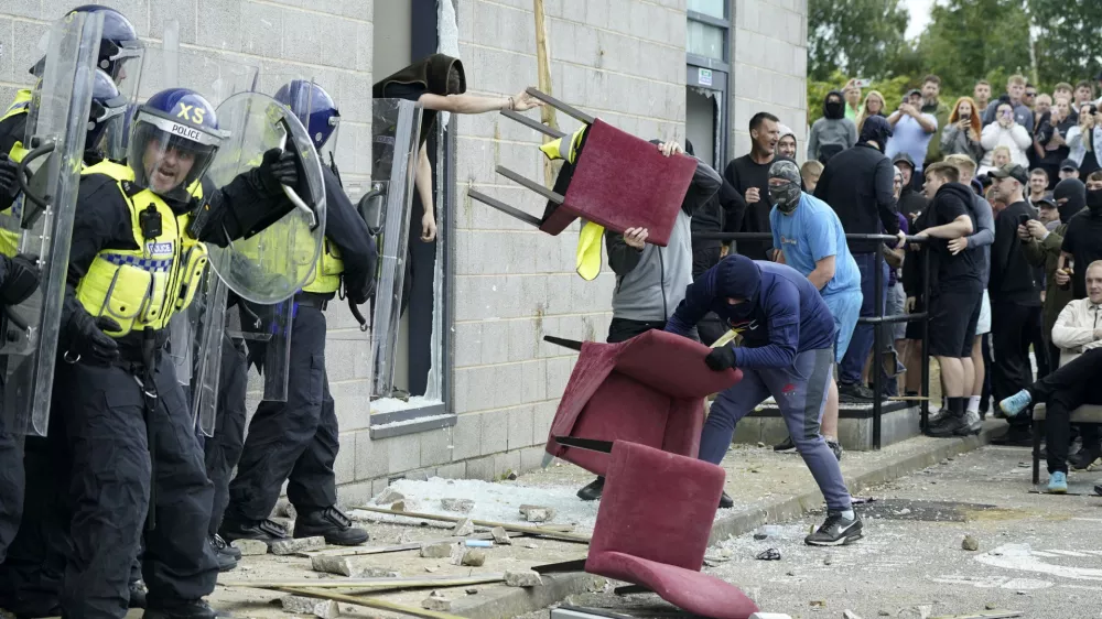 A chair is thrown at police officers as trouble flares during an anti-immigration protest outside the Holiday Inn Express in Rotherham, England, Sunday Aug. 4, 2024. (Danny Lawson/PA via AP)