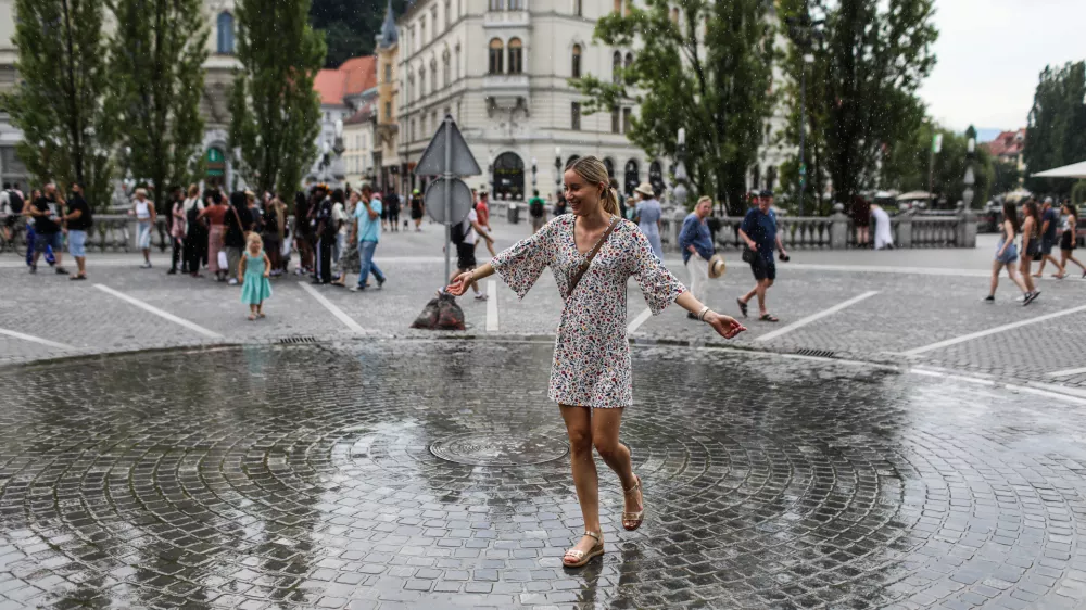 - Mimoidoči v Ljubljani se sku&scaron;ajo ohladiti na Pre&scaron;ernovem trgu, kjer je in&scaron;talacija Zmaga Modica ljubljansko lastno vreme.- 10.07.2024. - Vročinski val je zajelSlovenijo s temperaturima preko 30 stopinj.//FOTO: Bojan Velikonja
