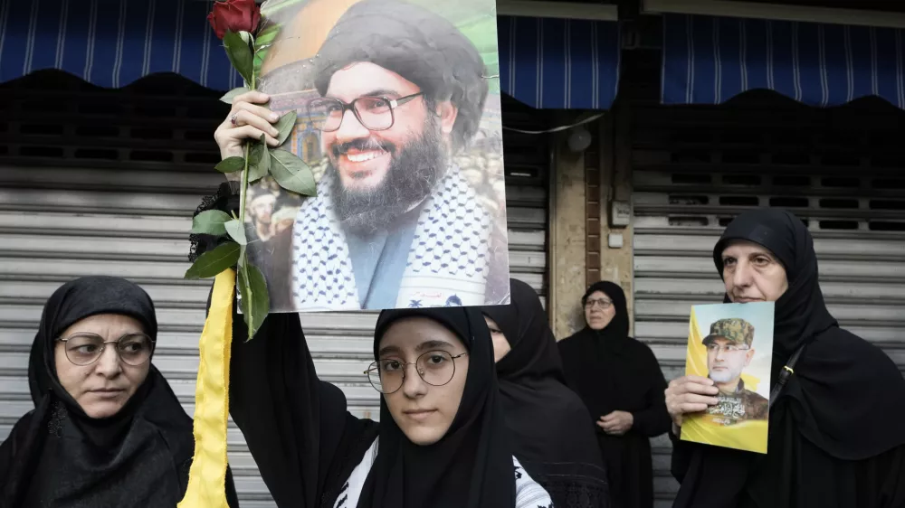 Hezbollah supporters carry pictures of Hezbollah commander Ibrahim Akil, right, and Hezbollah leader Hassan Nasrallah, centre, during Akil's funeral procession in Beirut's southern suburb, Sunday, Sept. 22, 2024. (AP Photo/Bilal Hussein)
