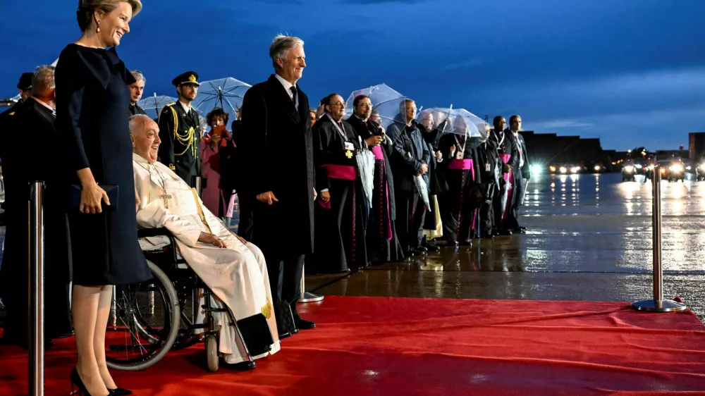 Pope Francis, flanked by Belgian King Philippe and Queen Mathilde, reacts after arriving at Melsbroek Military Air Base for a four-day apostolic journey, in Steenokkerzeel, Belgium, September 26, 2024. Vatican Media/&shy;Handout via REUTERS  ATTENTION EDITORS - THIS IMAGE WAS PROVIDED BY A THIRD PARTY.