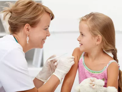 Brave little girl receiving injection or vaccine with a smile