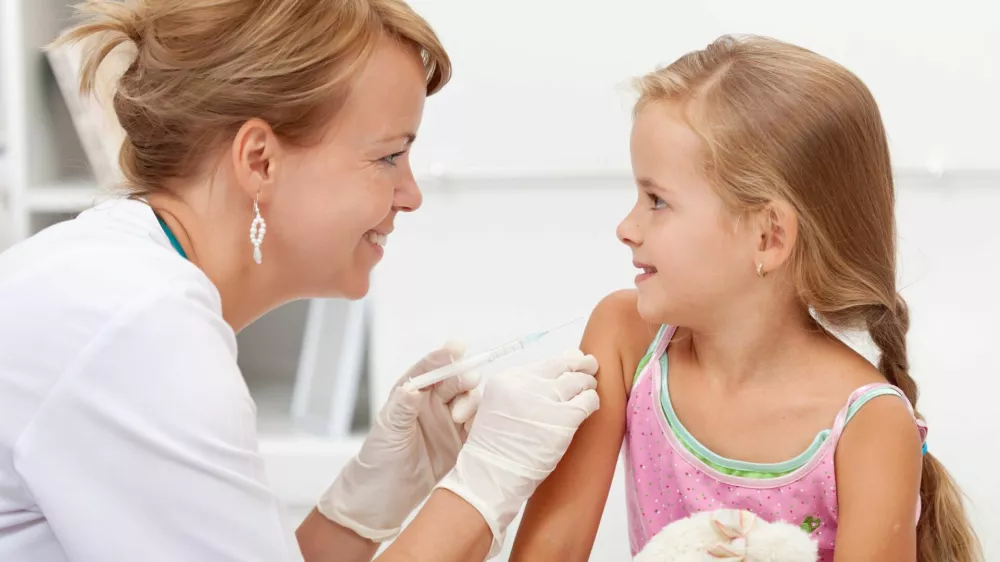 Brave little girl receiving injection or vaccine with a smile