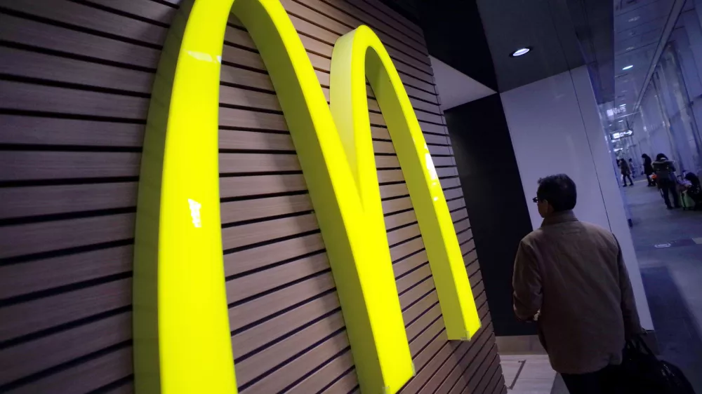 FILE - In this Dec. 17, 2014 file photo, a man walks by a McDonald's logo in front of its restaurant in Tokyo. McDonald's is set to unveil its latest plans to revive its sputtering business on Monday, May 4, 2015. (AP Photo/Eugene Hoshiko, File)