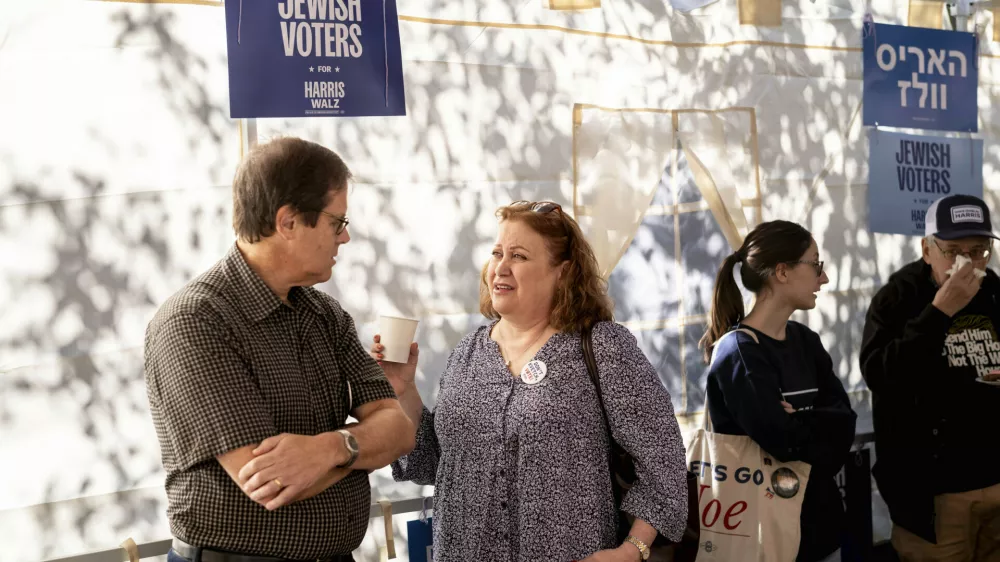 Mark and Suzan Lopatin gather with other supportes of Democratic presidential nominee Vice President Kamala Harris in a Sukkot before going door to door to canvass Jewish voters Sunday, Oct. 20, 2024. (AP Photo/Laurence Kesterson)
