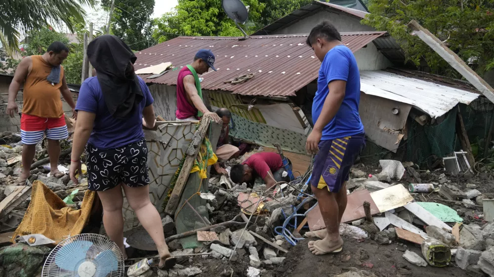 Residents try to recover personal belongings from their damaged home after a landslide triggered by Tropical Storm Trami recently struck Talisay, Batangas province, Philippines, Saturday, Oct. 26, 2024. (AP Photo/Aaron Favila)