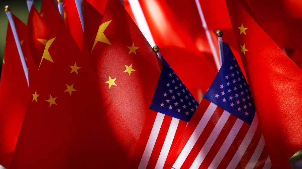 In this Sept. 16, 2018, photo, American flags are displayed together with Chinese flags on top of a trishaw in Beijing. The American Chamber of Commerce in China says Beijing will "dig its heels in" after U.S. tariff hikes and appealed for a negotiated end to their trade battle. The chamber on Tuesday, Sept. 18 warned a "downward spiral" appears certain after President Donald Trump approved a tariff hike on $200 billion of Chinese imports in a dispute over Beijing's technology policy. (AP Photo/Andy Wong)